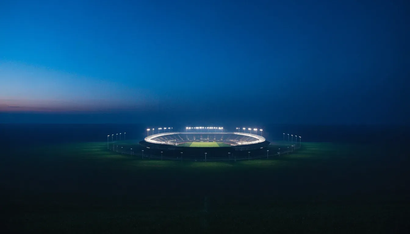 Ein Stadion unter Flutlicht aus großer Entfernung gesehen, der Himmel darüber ist tiefblau.