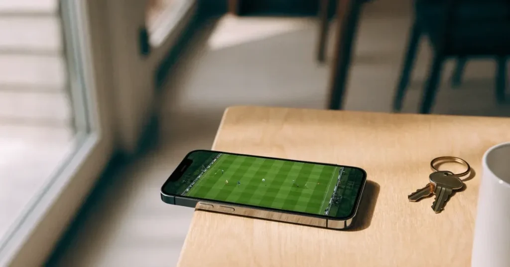 Ein Smartphone mit dunklem Display liegt auf einem hellen Tisch neben einem Schlüsselbund, Tageslicht fällt von der Seite ein.